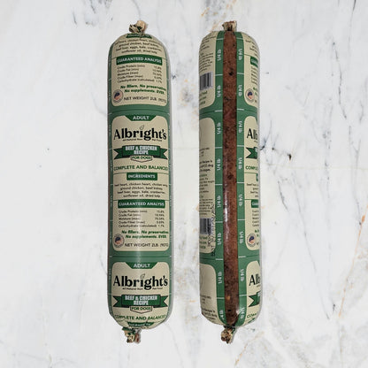 Two packages of Albright's beef and chicken dog food on a marble surface