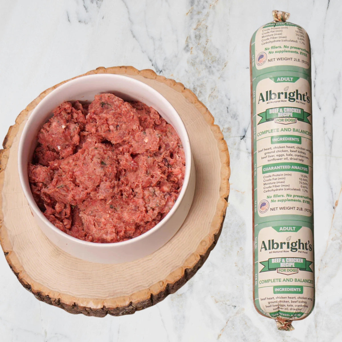Bowl of raw pet food next to a tube of Albright's pet food on a marble surface