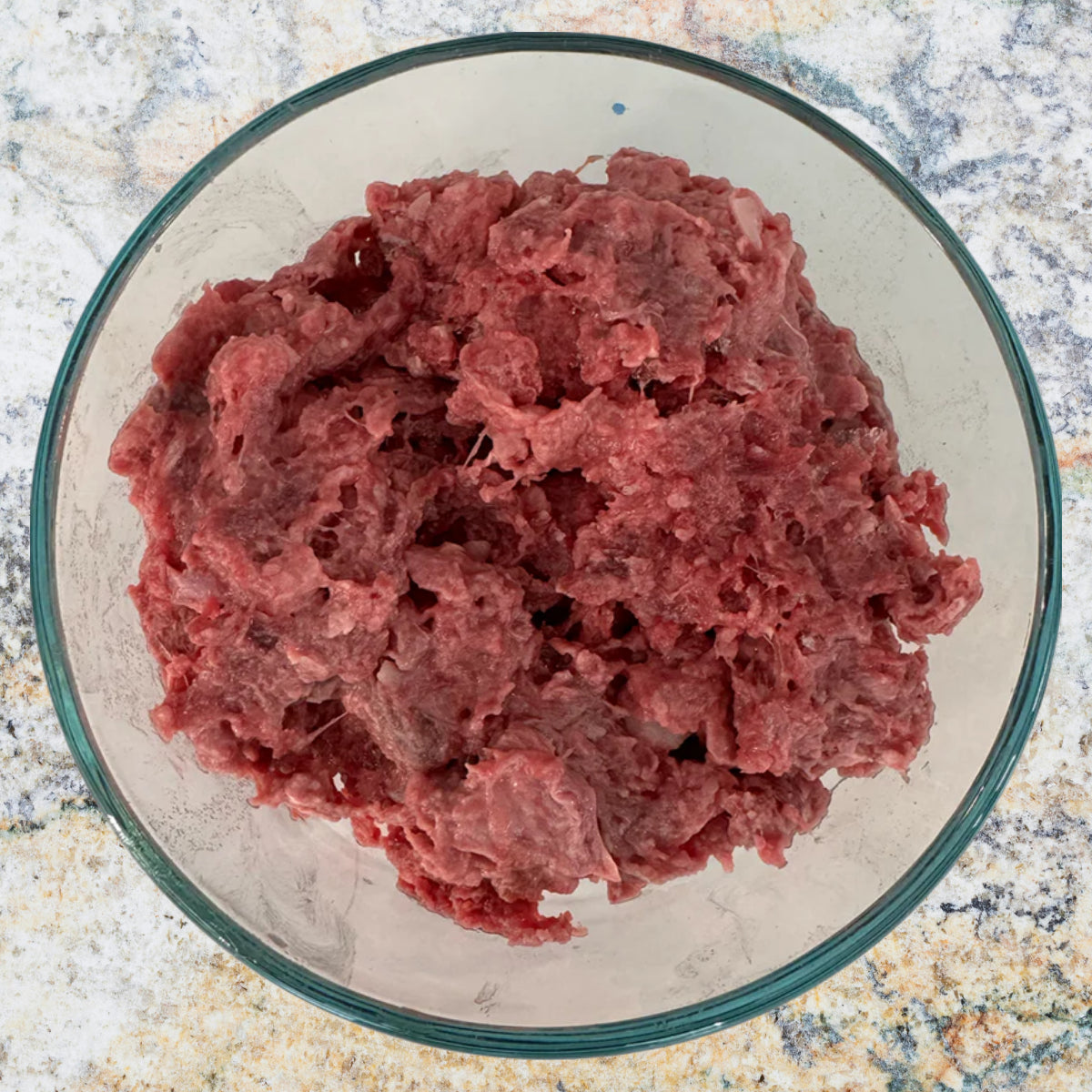 Bowl of raw ground venison prey model dog food, part of an 80/10/10 raw diet, sold by Benny’s Raw Dog Food