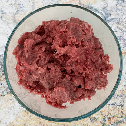 Bowl of raw ground venison prey model dog food, part of an 80/10/10 raw diet, sold by Benny’s Raw Dog Food