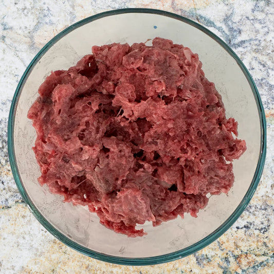 Bowl of raw ground venison prey model dog food, part of an 80/10/10 raw diet, sold by Benny’s Raw Dog Food